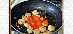 adding sriracha sauce to the shrimp in the pan.