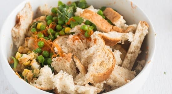 mixing all the ingredients together including, bread, green peas, and potato.