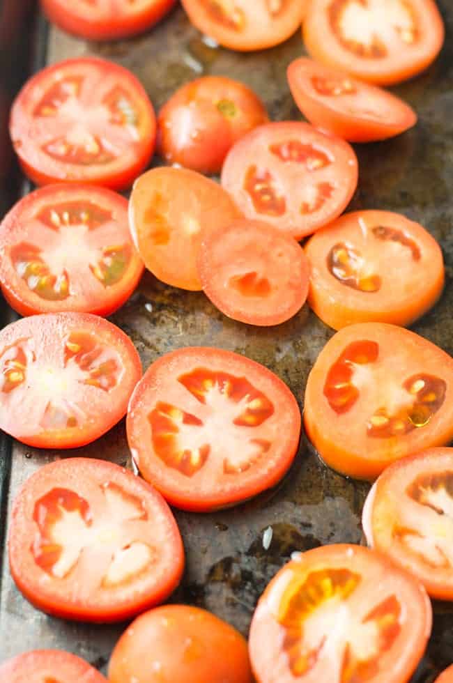 Tomato is sliced to roast in the oven.