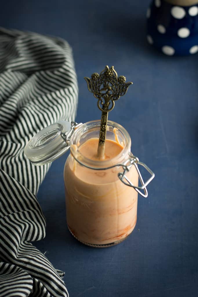 Boom boom sauce is stored in a decorative glass bottle with the spoon.