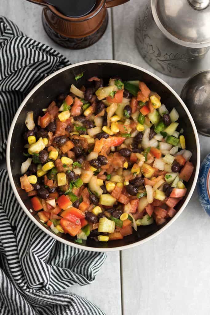 This Fiesta salad recipe is a crowd-pleasing dish. This Mexican style salad is delicious with bright flavors, made with corn, black bean, and red peppers.