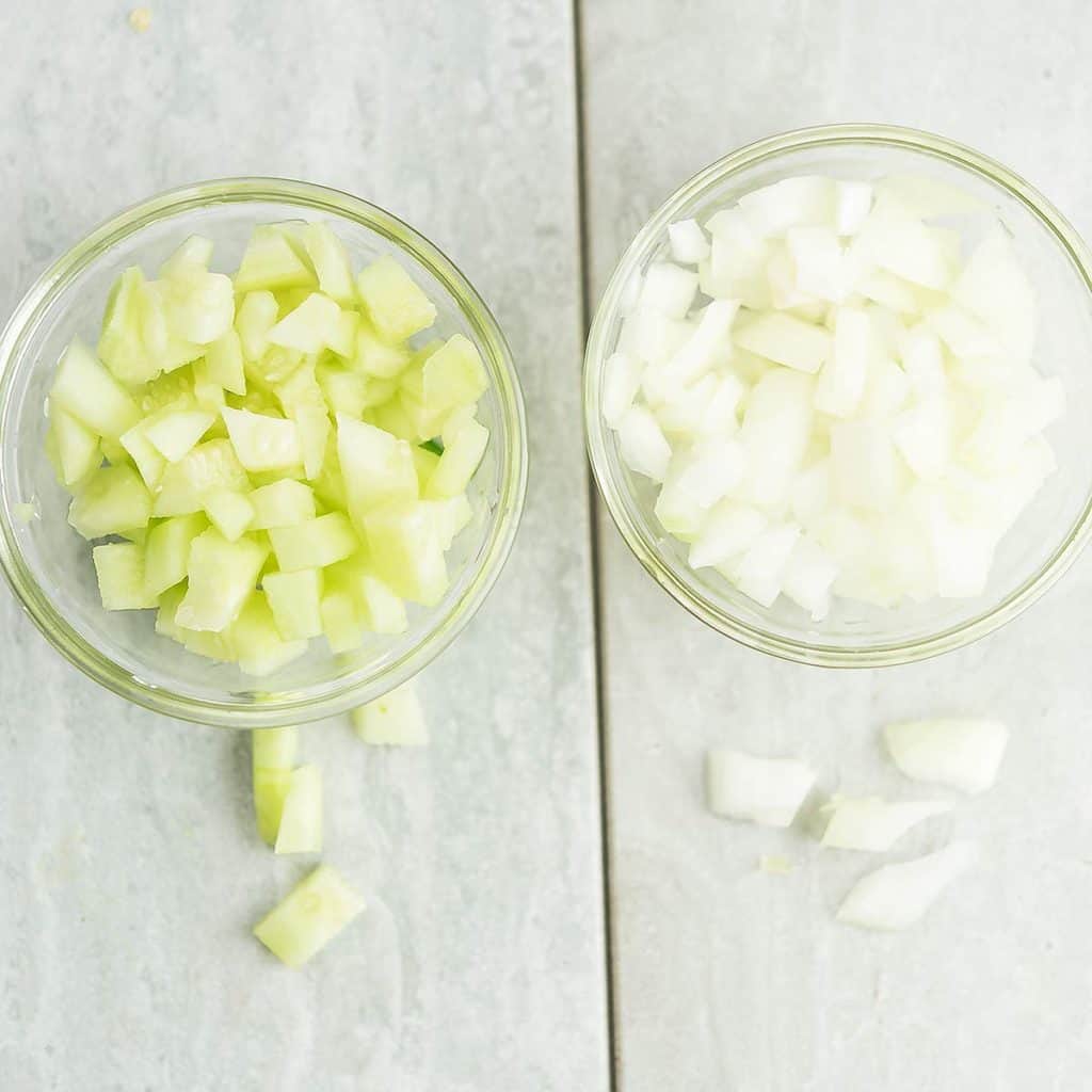 cucumber and onion cut into cubes and kept in glass bowls for making bright freshii salad.