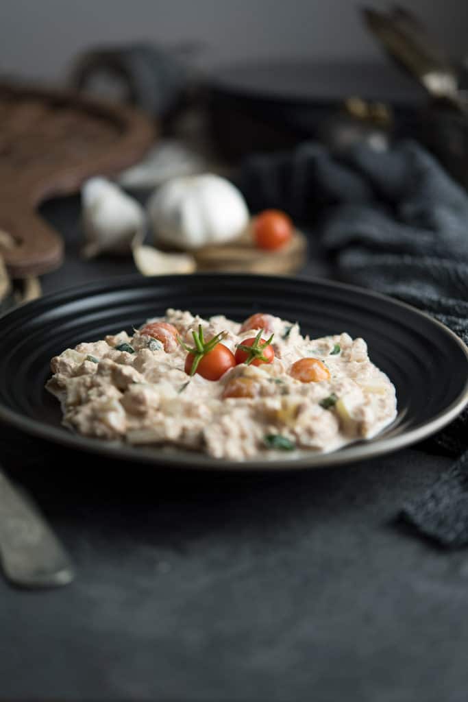 Cherry tomatoes are added as garnish over spicy tuna salad.