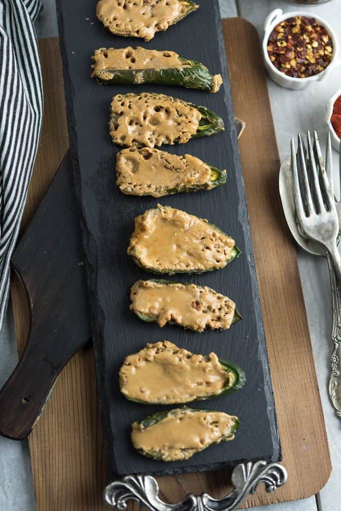 Peanut butter stuffed jalapenos served for game day in a cedar tray. 