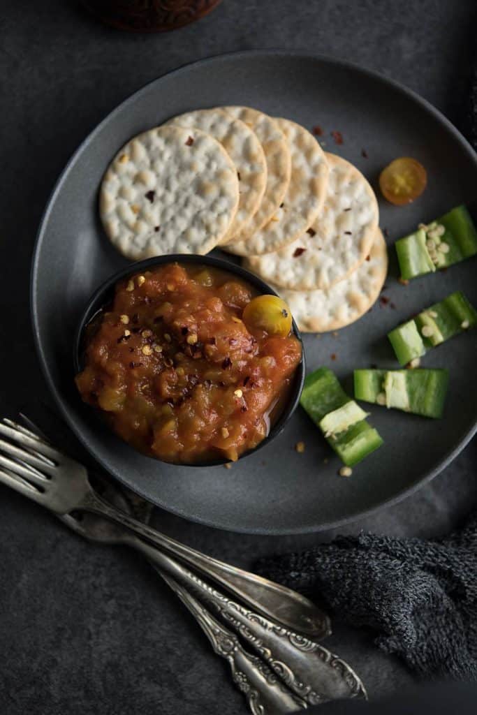 Spicy roasted jalapeno salsa in a black bowl with red pepper flakes for added heat.