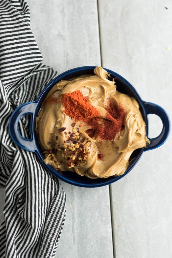 Peanut butter in a blue bowl with cayenne pepper, paprika, and peanut butter.