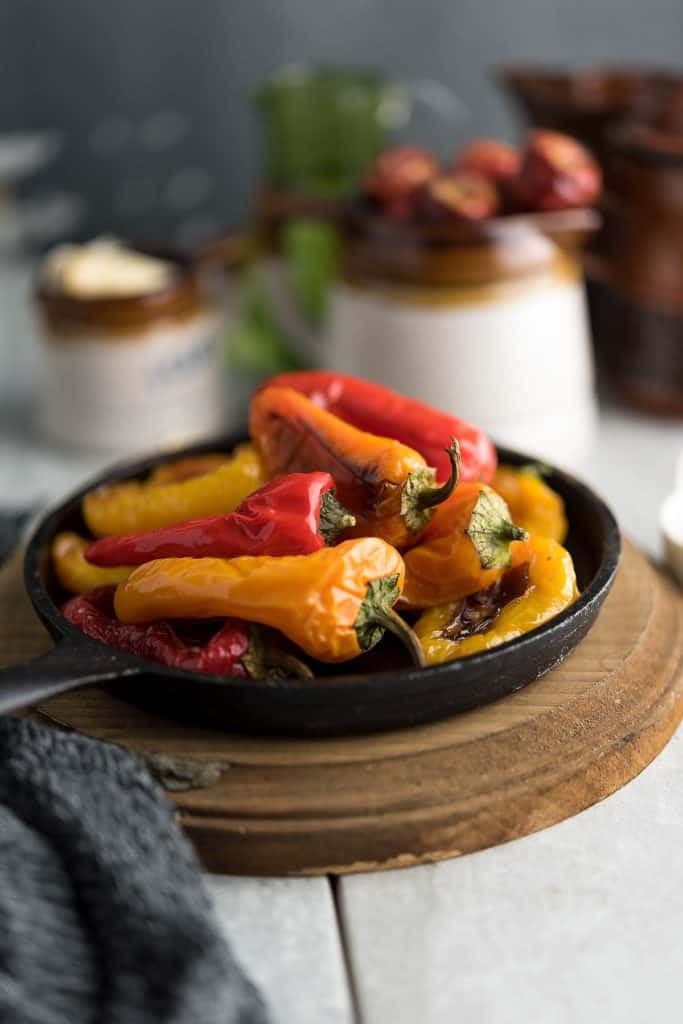 Roasted sweet mini peppers are served in a black sizzling plate.