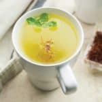 saffron tea served in a cup, garnished with mint leaves