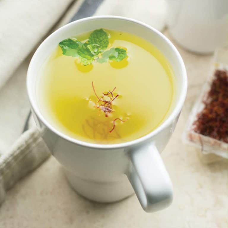 saffron tea served in a cup, garnished with mint leaves