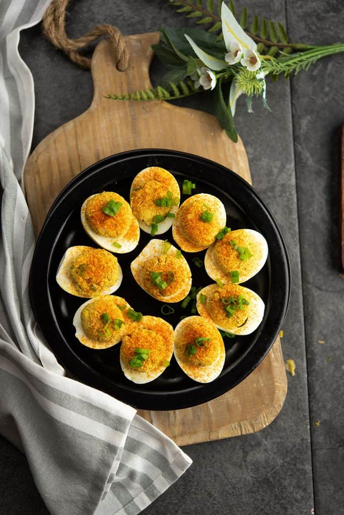 Cajun deviled eggs are placed in a serving wooden platter.