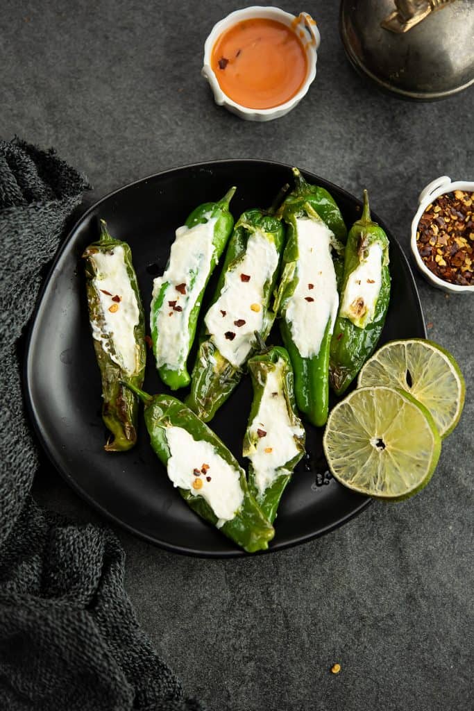 Stuffed Shishito peppers placed over a black plate 