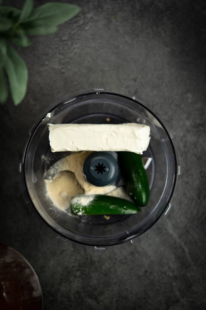 The ingredients for jalapeno cream cheese in a food processor jar