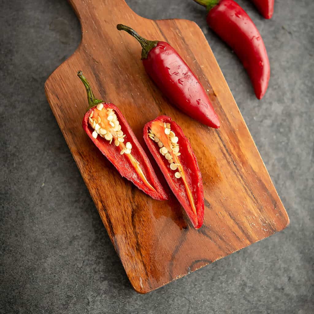 Fresno peppers with seeds shown in the cutting board