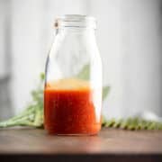 honey sriracha wing sauce in stored in a clear glass jar, ready to toss chicken wings