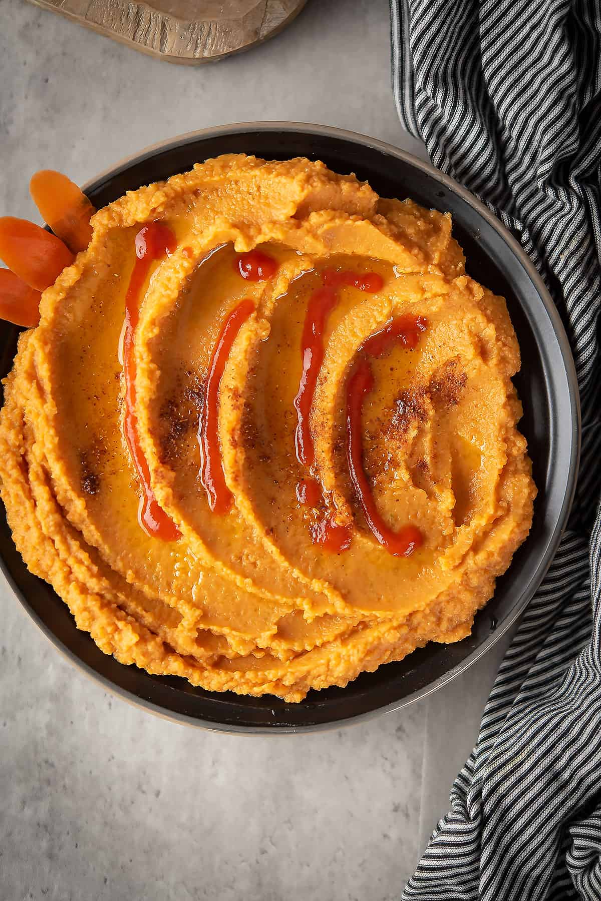 This creamy, sweet and spicy  carrot Sriracha hummus in the black plate