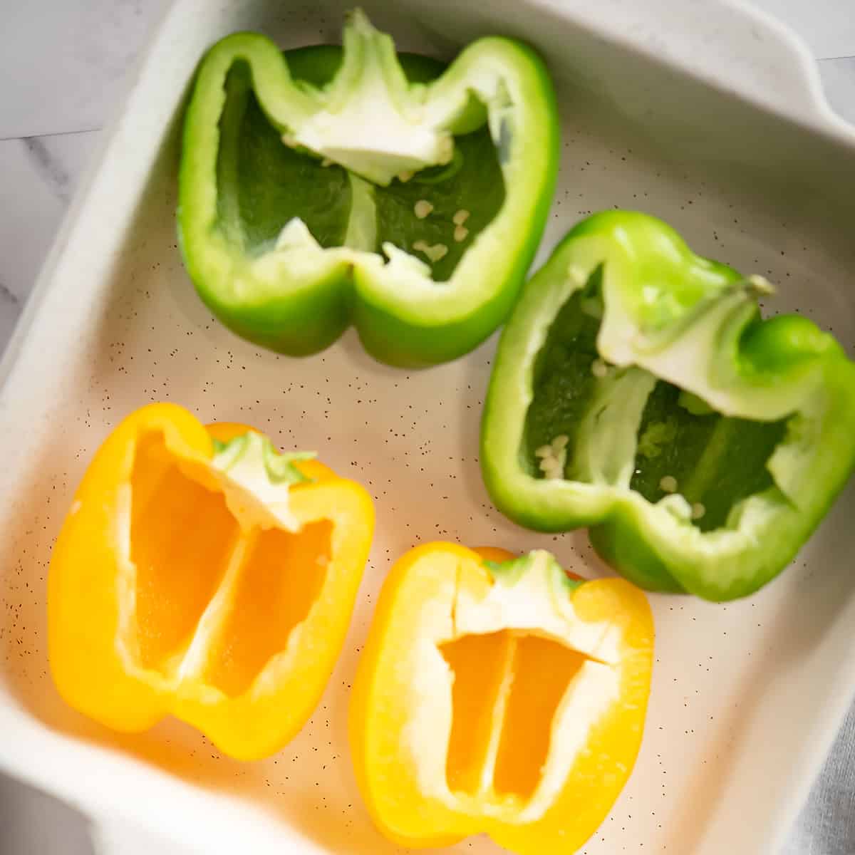 bell peppers are sliced into half in a casserole