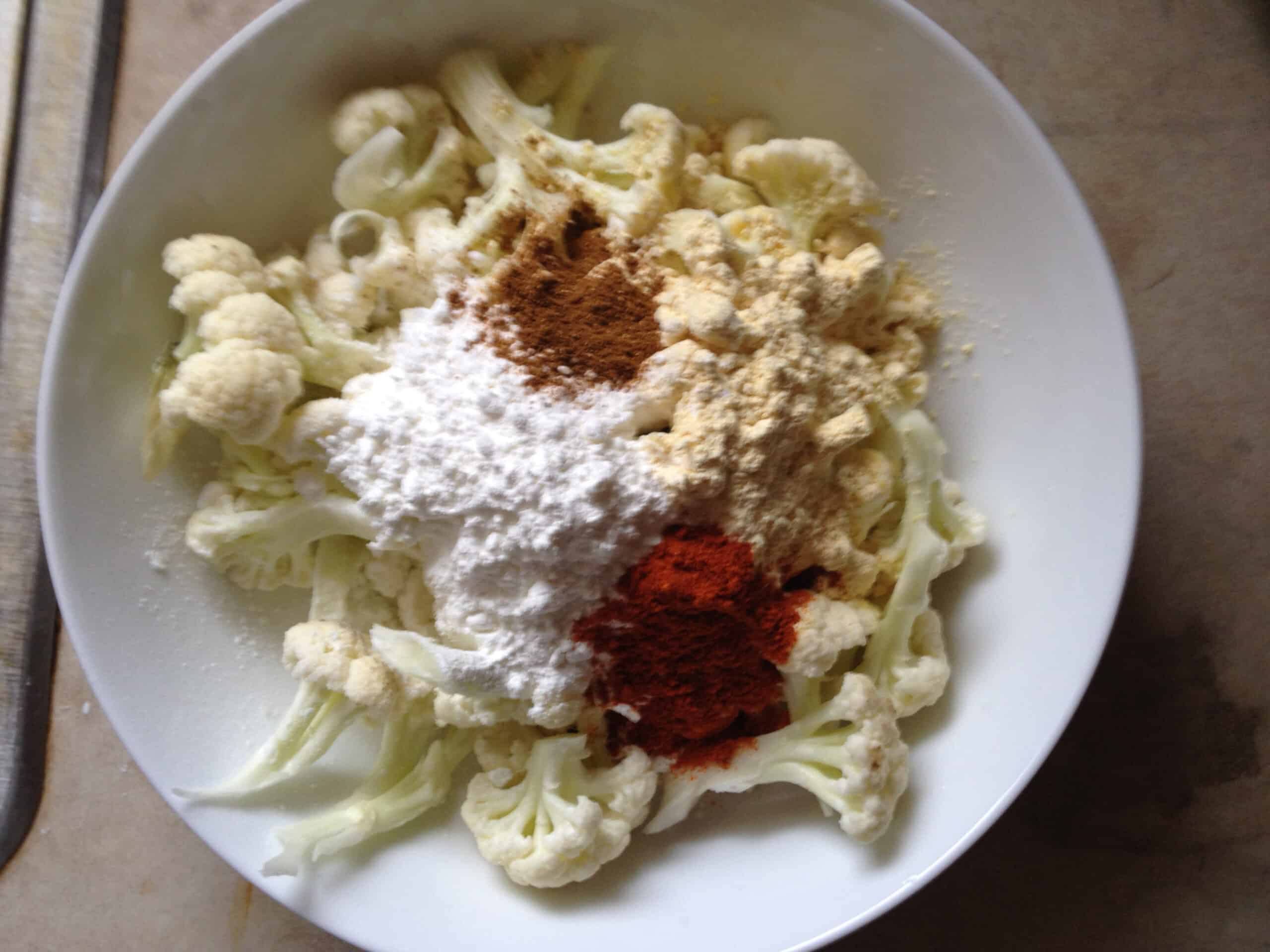 adding all the spices to cauliflower florets