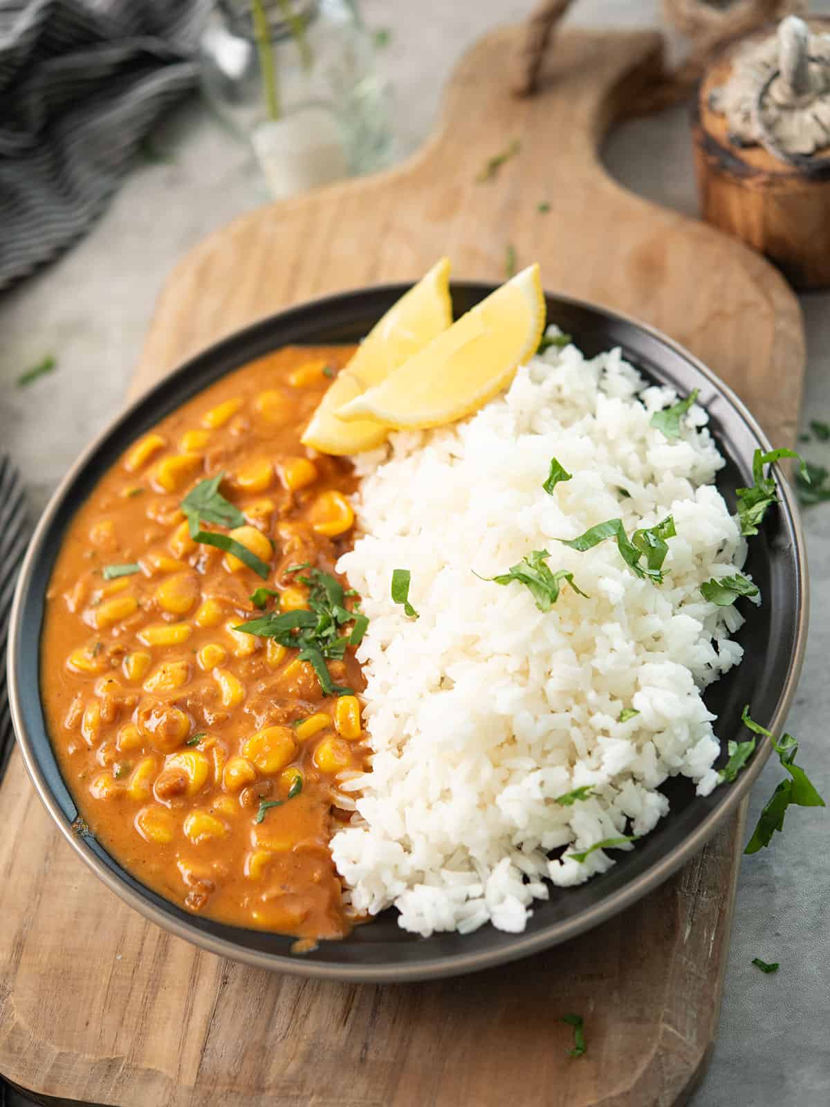 corn curry garnished with cilantro and lemon wedges