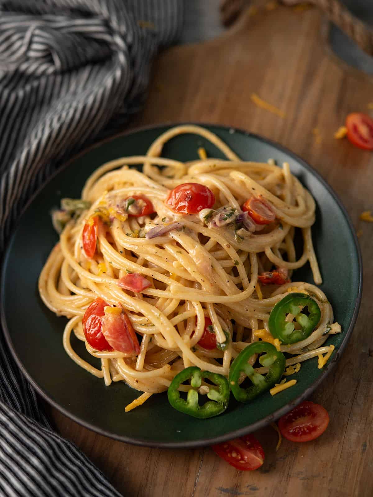 jalapeno spaghetti served in a plate garnished with cherry tomatoes and jalapeno slices