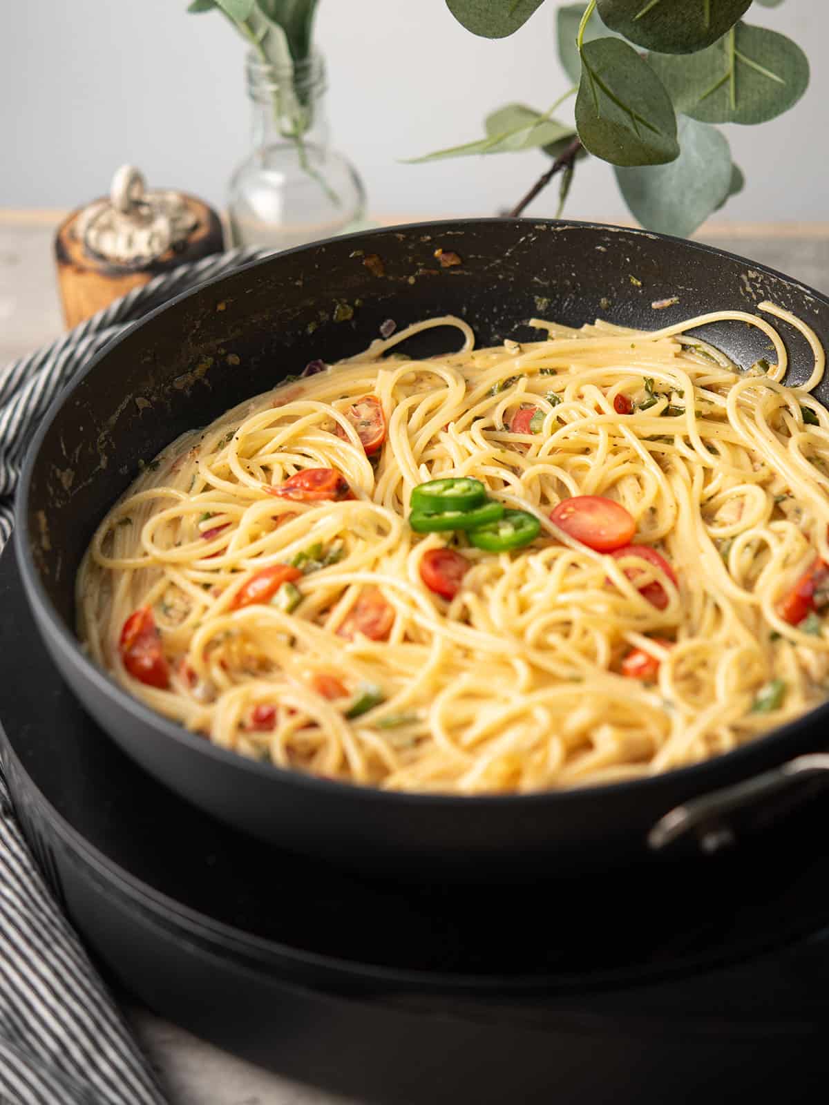 the cooked jalapeno spaghetti over the pan with jalapenos slices as the garnish