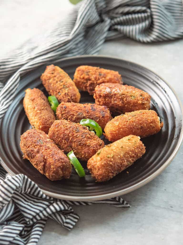 Jalapeno Cheese Sticks placed in a plate with jalapeno slices as garnish with kitchen towel