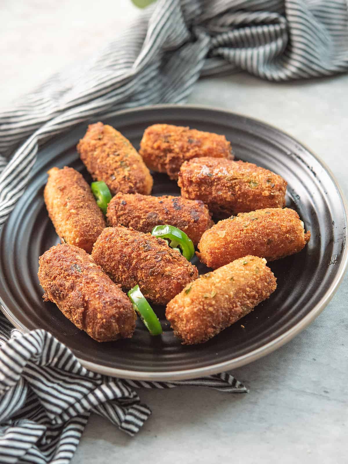 crispy jalapeno cheese sticks served in a plate garnished with jalapeno slices