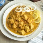instant pot chicken curry served in a plated with onion rings and lemon slices