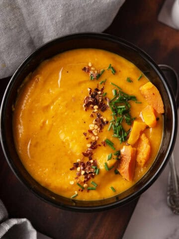 Butternut squash soup in a rustic wooden bowl with a slice of crusty bread