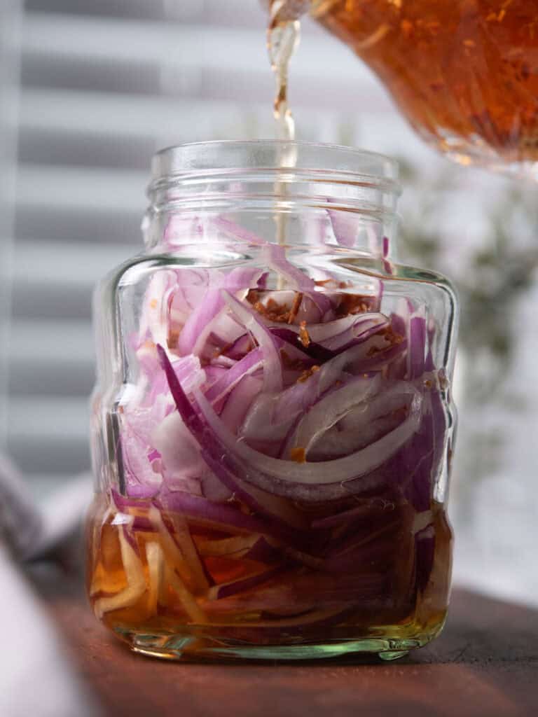 filling the spicy mixture into the jar to make spicy pickled onion