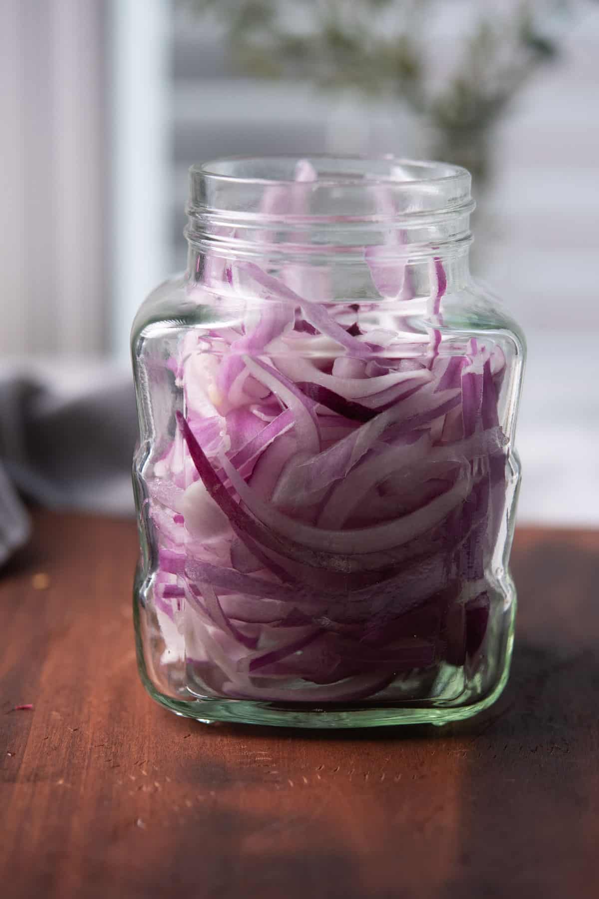 steps 1 of the recipe, stuffing onion slices in a container