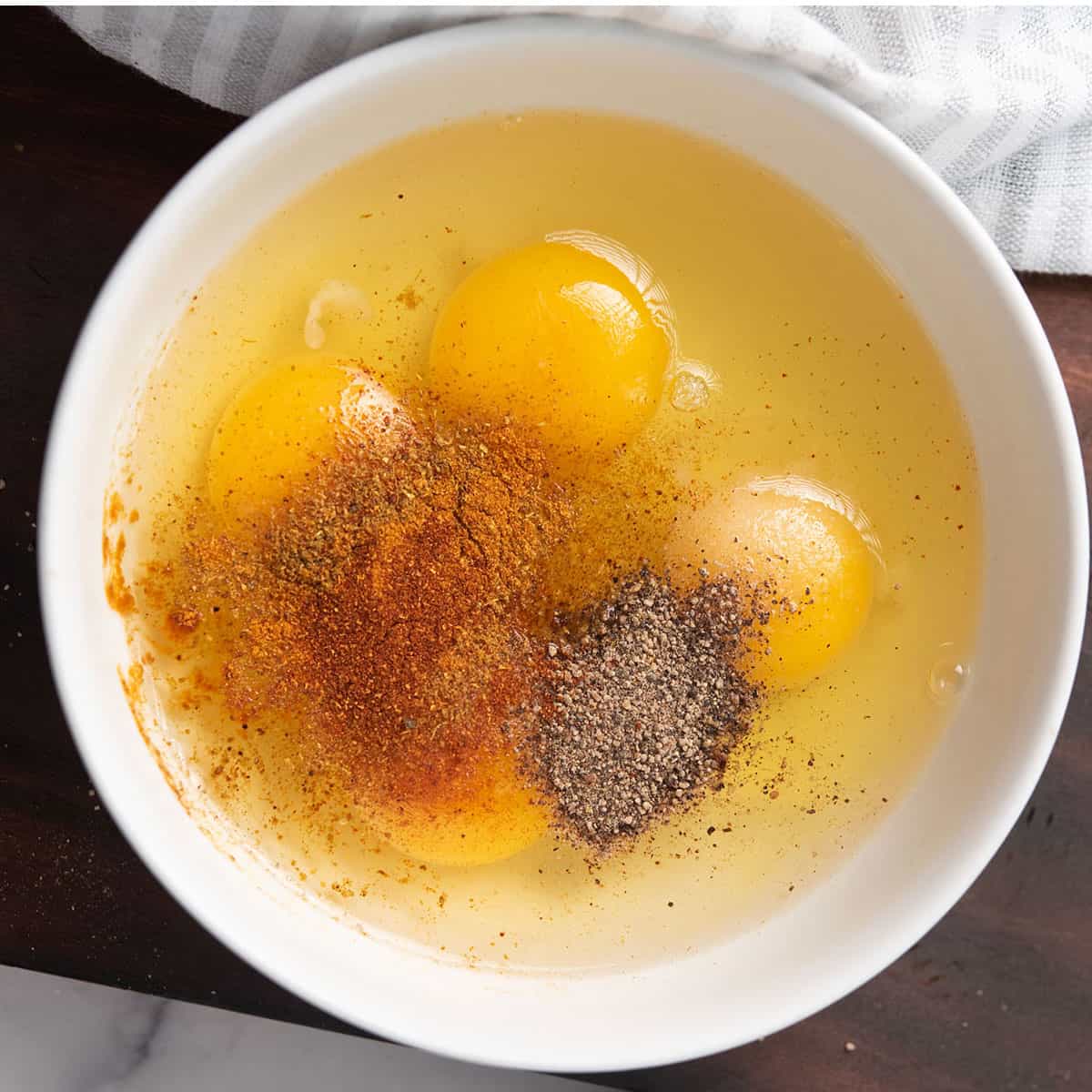 A bowl with egg and spices for making cajun scrambled eggs