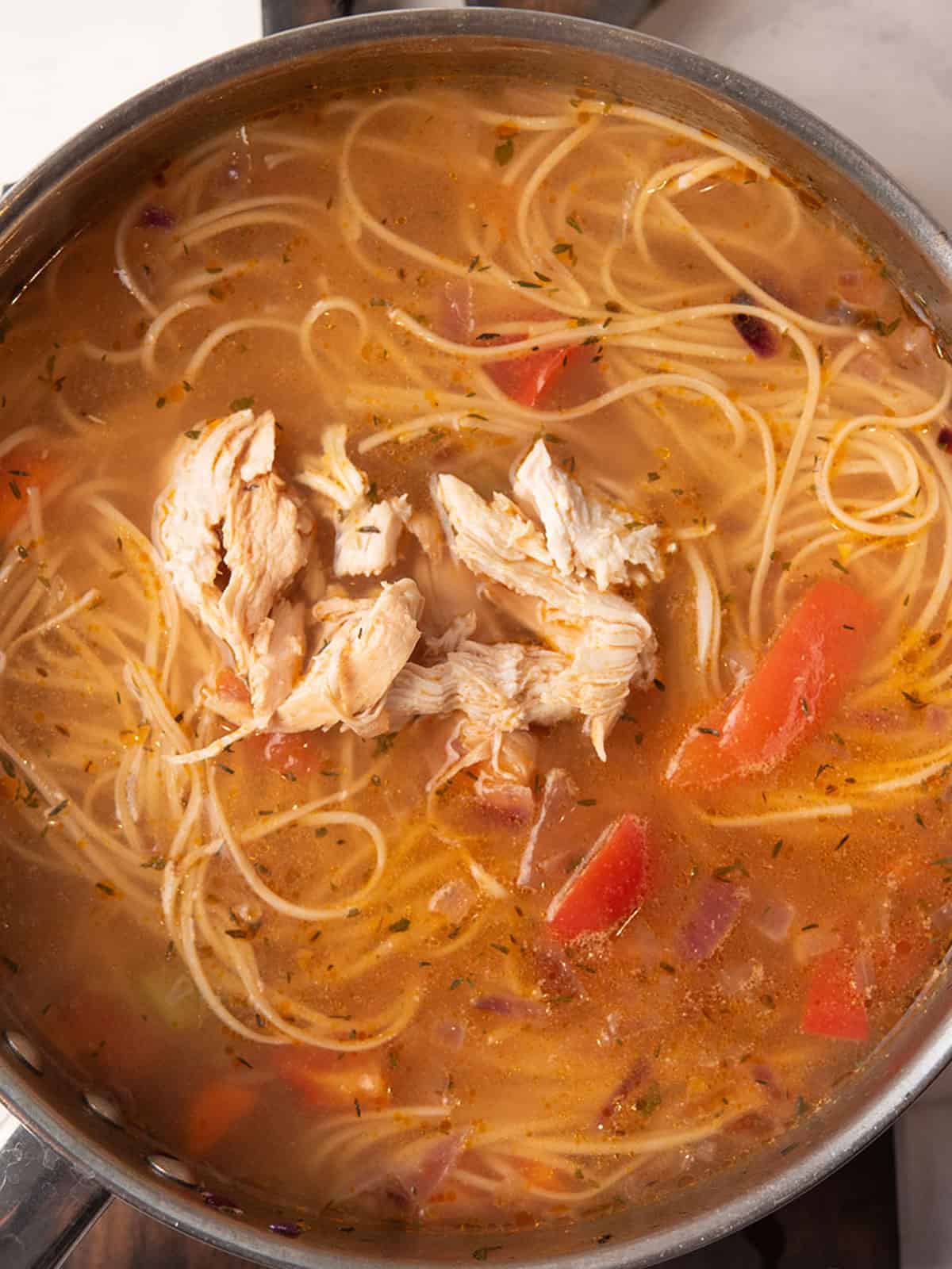 shredded chicken added back to the pan for making Spicy chicken noodle soup