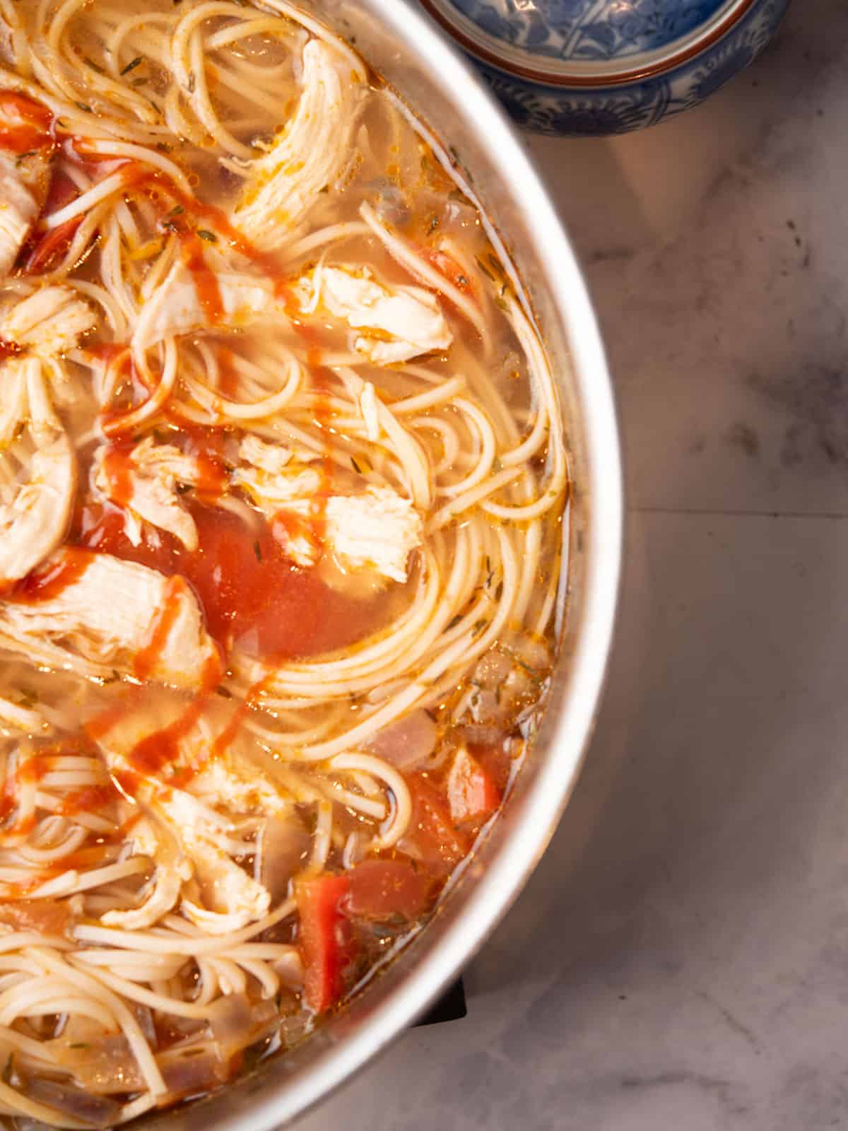  Spicy chicken noodle soup drizzled with spicy sriracha sauce for serving