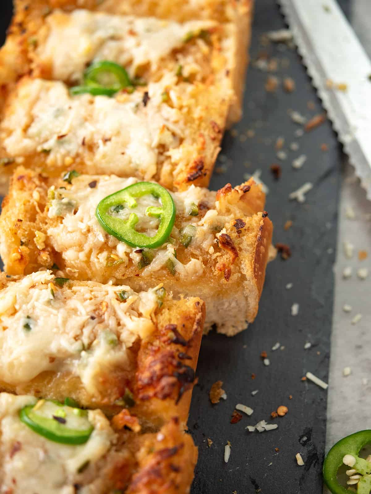 5 slice of jalapeno garlic bread over black tray with cheese crust on the sides