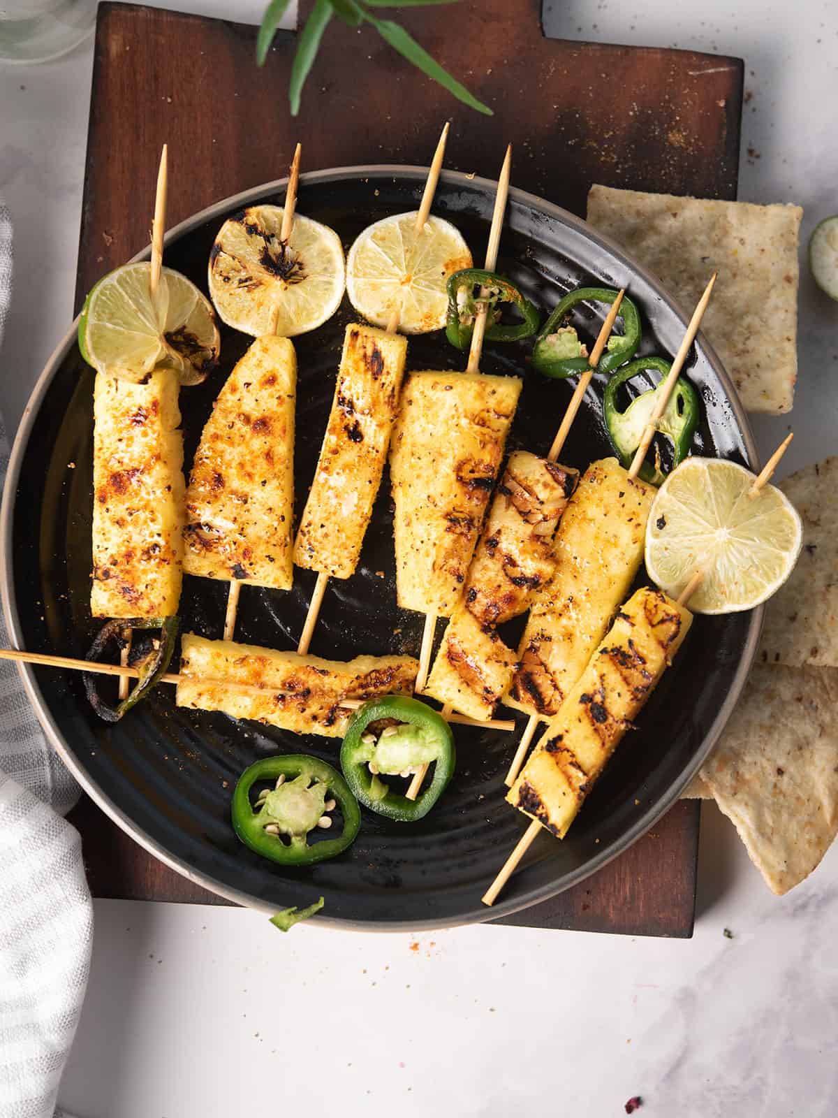 Spicy Grilled Pineapple served in a plate with lemon and jalapeno slices