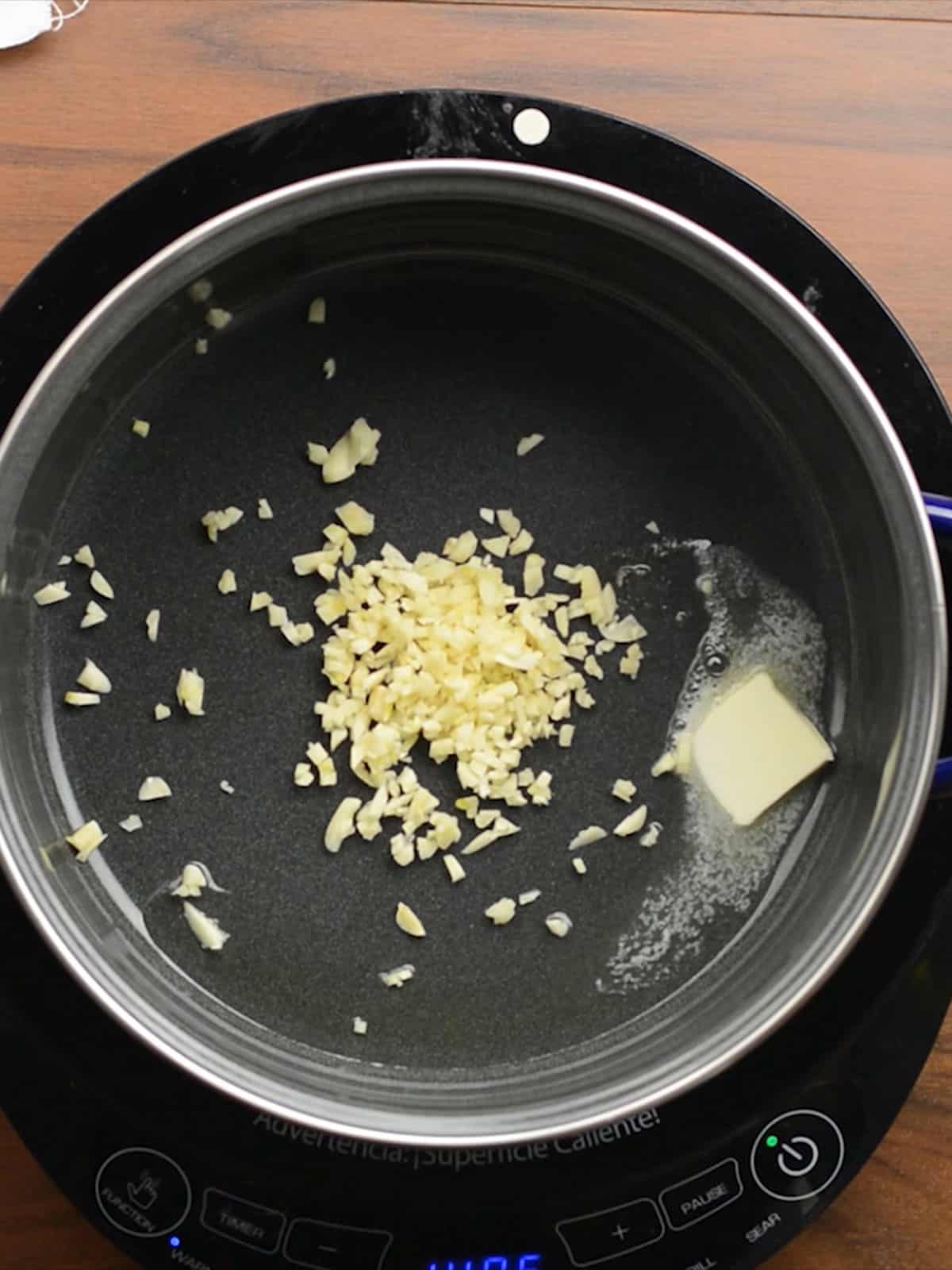 Sautéing garlic in butter and oil for Hawaiian shrimp preparation.