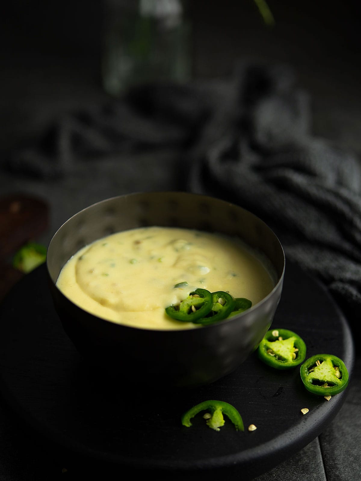 Close-up of a bowl of jalapeño cheese sauce with jalapeño slices on top, ready to serve.
