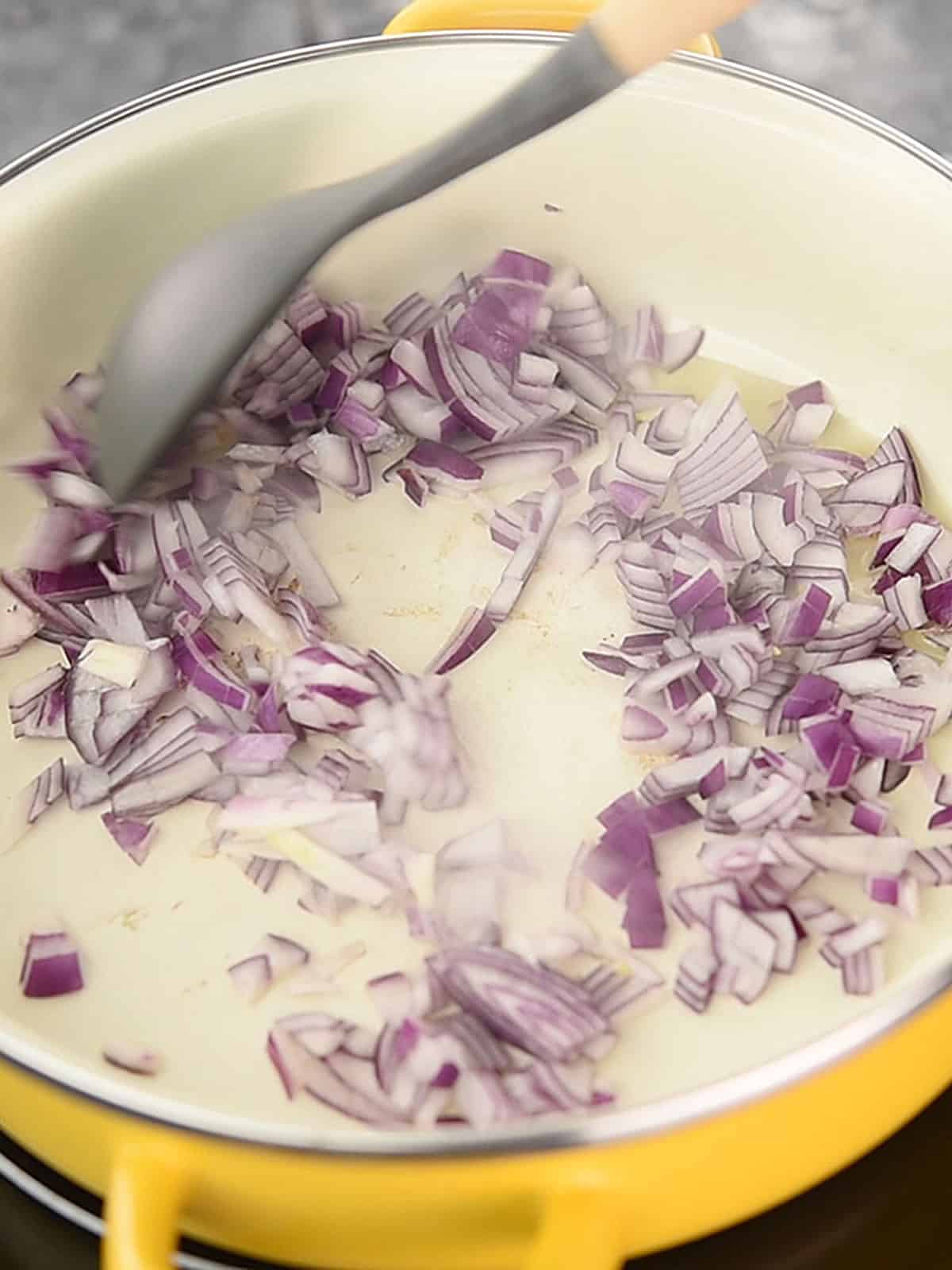 Sautéing chopped onions in a pan over medium heat for the stuffing.
