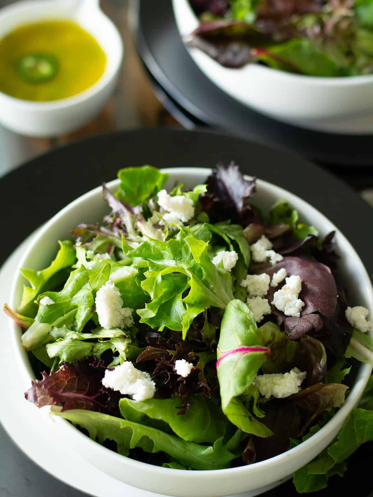 Tossing the spring mix greens with fresco cheese in a large bowl.