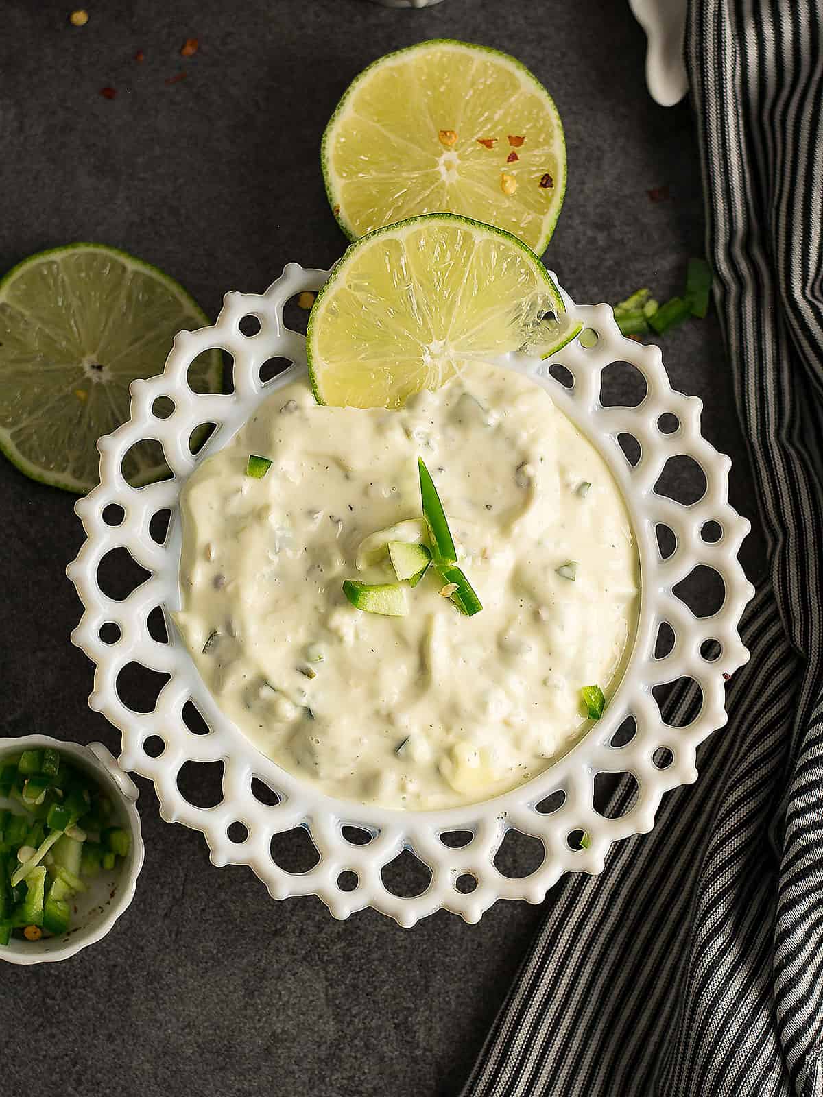 Creamy jalapeno aioli served in a white bowl, garnished with fresh jalapeno slices.