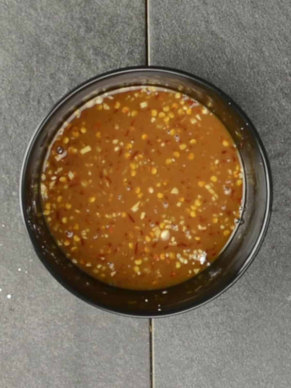 Combining soy sauce, chili garlic sauce, and jalapeno slices in a small bowl