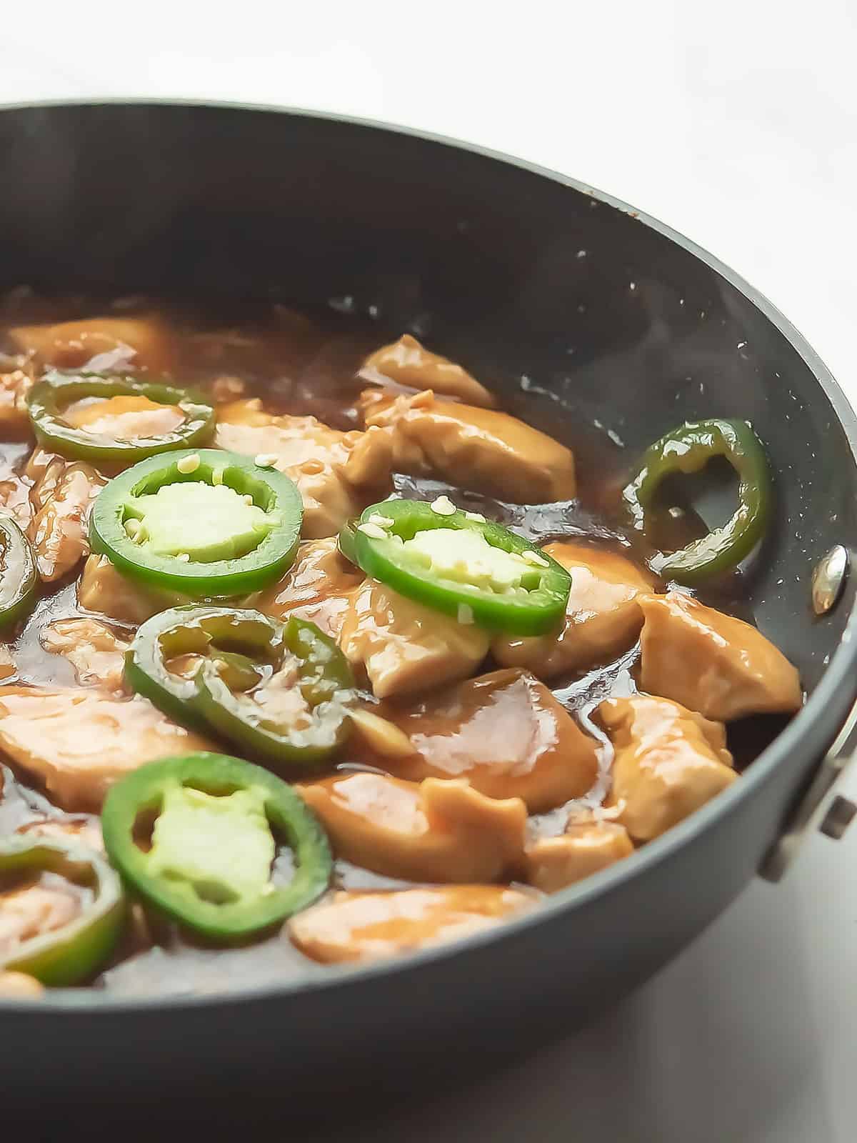 Cooking chicken in a pan with oil until fully cooked and sautéed