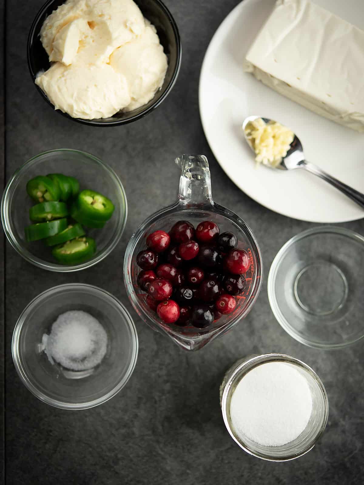 Ingredients for cranberry jalapeno dip including cream cheese, cranberries, and jalapenos.