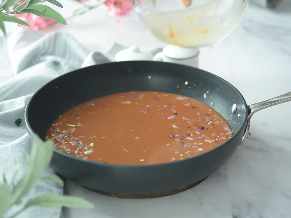 Simmering black pepper sauce in a pan on the stove.