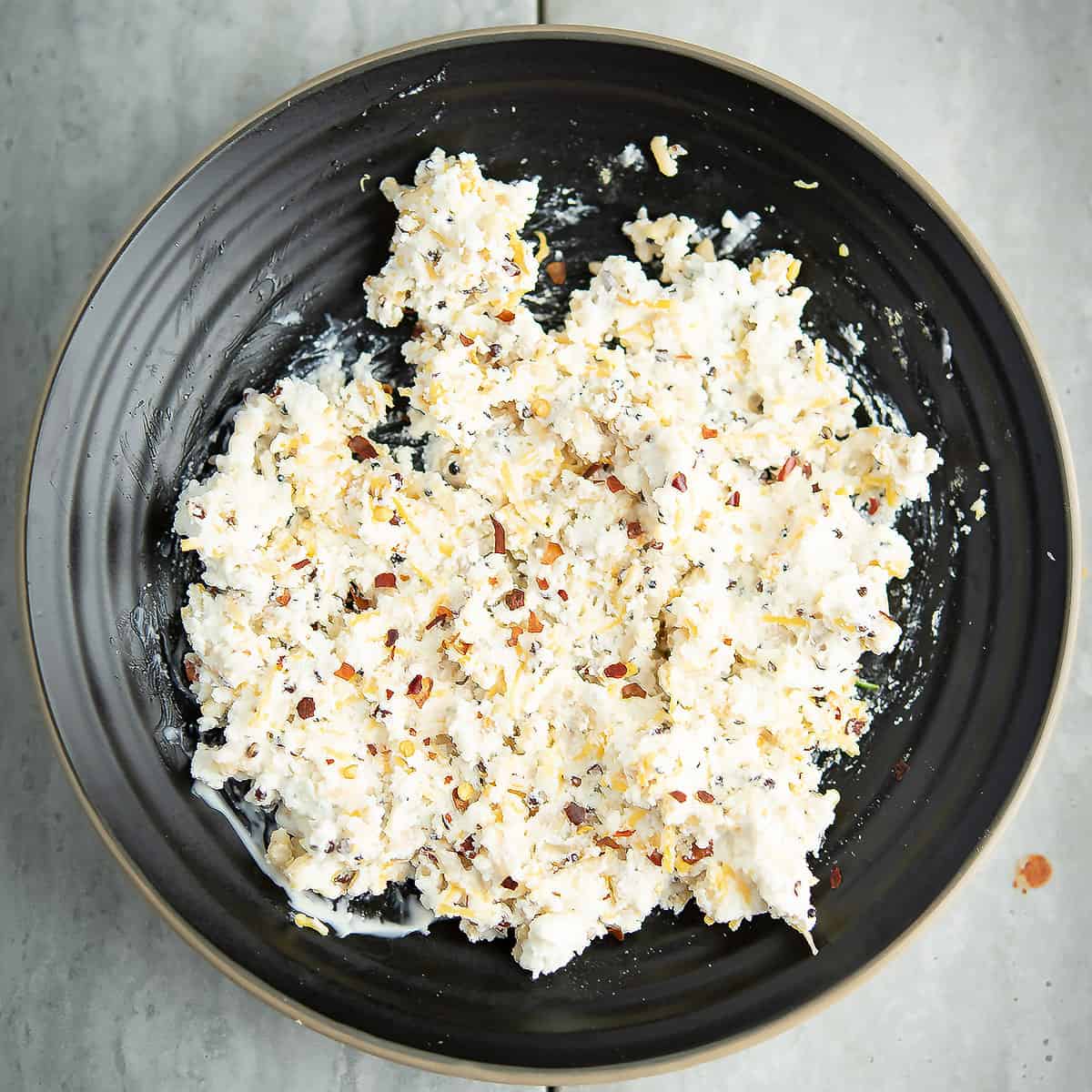 Mixing bowl with cream cheese, cheddar cheese, mayonnaise, and spices for stuffing.