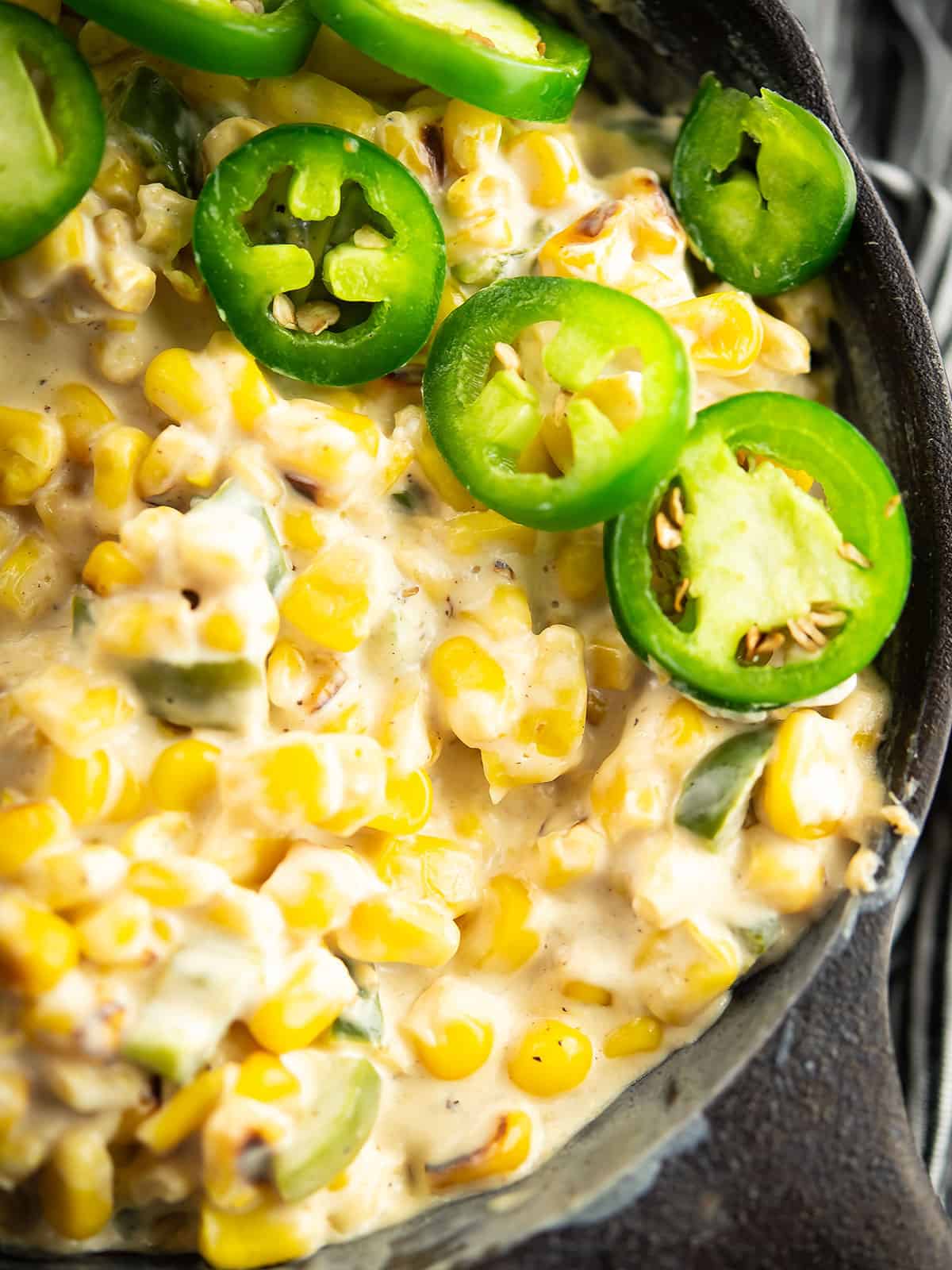 Close-up view of creamy jalapeno corn with jalapeno slices on top