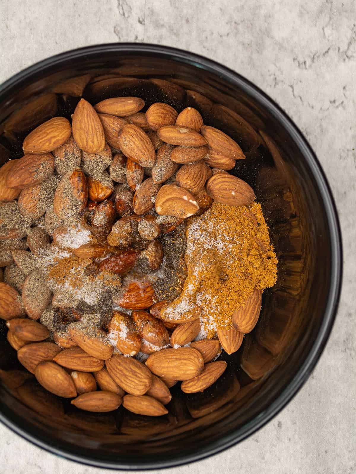 Mixing almonds with melted butter and spices in a bowl.