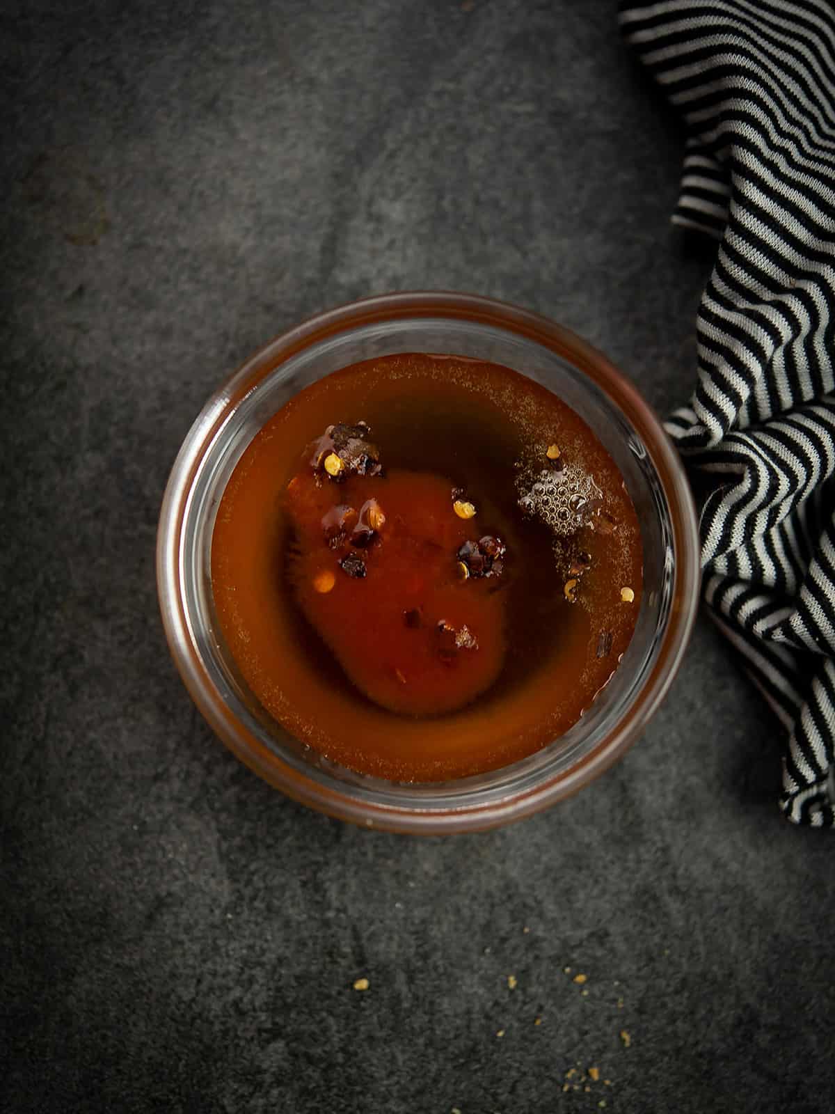 Mixing bowl with honey and roasted red peppers over simmering water.