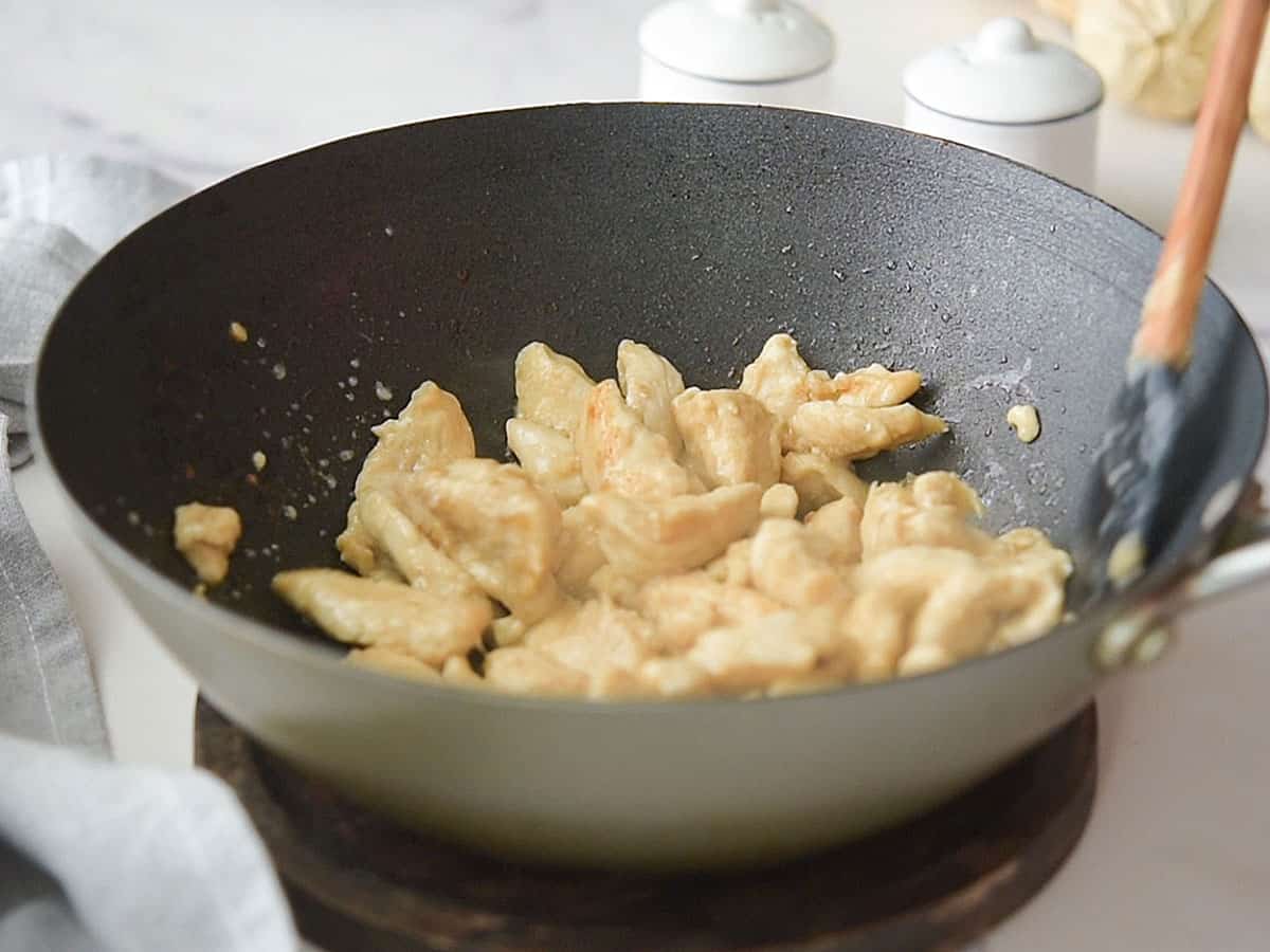 Chicken cooking in a pan over medium heat.