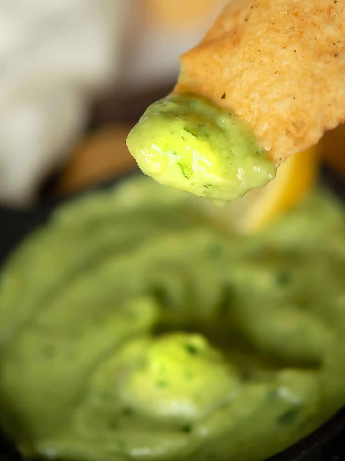 jalapeno avocado sauce is dipped into the cracker
